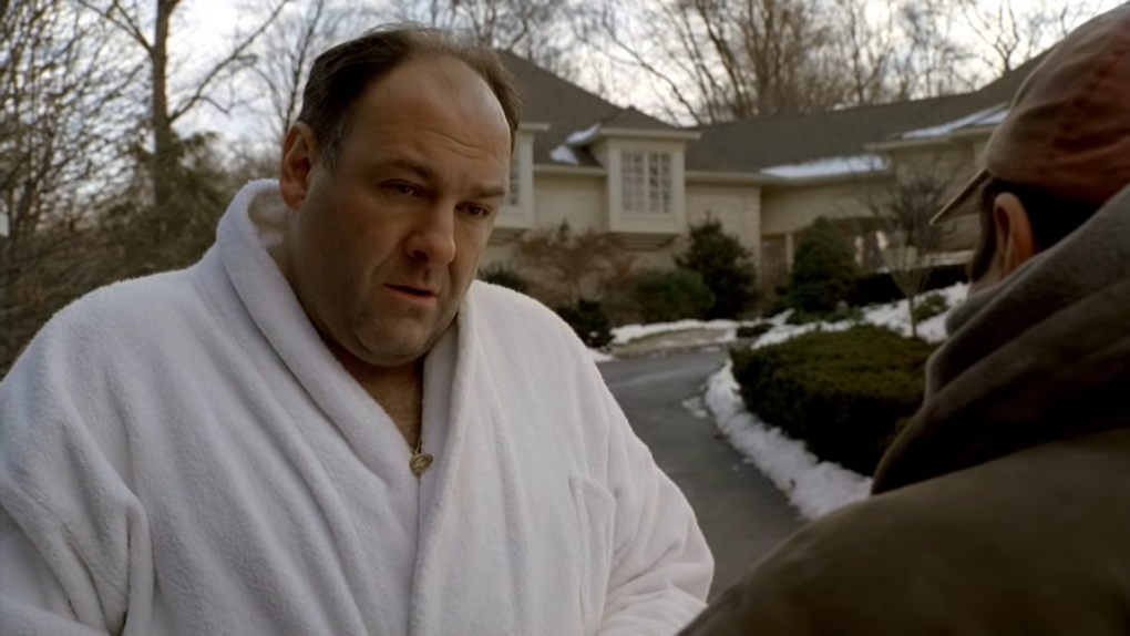 Sal Iaccuzzo in a white robe standing outside in front of man in a hat near the building
